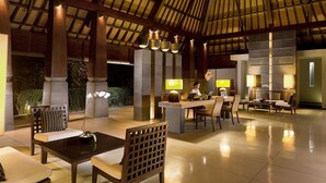 A spacious lobby with a high ceiling, large pillars, and a seating area with tables and chairs.