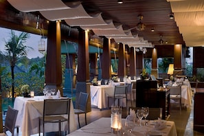 En restaurang med bord som är dukade för middag, och som erbjuder utsikt över omgivningarna.