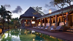 A resort with a pool, lounge chairs, and a covered dining area.