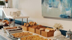 A buffet with various food items, including bread and pastries, and a painting on the wall. - MIA Urban Agadir (Agadir)