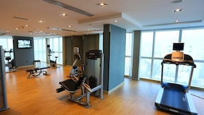 Un gimnasio con equipo de cardio, máquinas de pesas y una cinta de correr.
