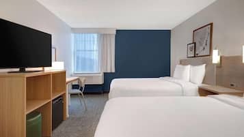 A hotel room with two beds, a desk, a television, and a window with curtains.