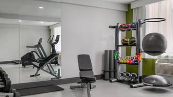 A gym with exercise equipment, a bench, and a mirror.