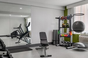 Un gimnasio con equipo de ejercicio, una banca y un espejo.