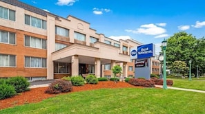 A hotel with a modern facade, a sign indicating it's a Best Western, and a well-maintained outdoor area with a pathway and landscaping.