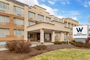 Un hotel con fachada moderna, un acceso cubierto y un cartel que indica el nombre 'Hotel Watertown'.