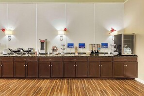 Uma área de recepção de hotel com um balcão comprido, armários e um espaço para café.
