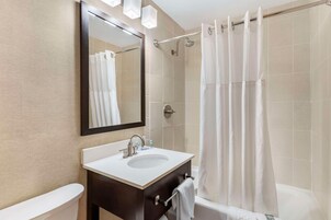 Un baño moderno con lavamanos, espejo y cortina de ducha.