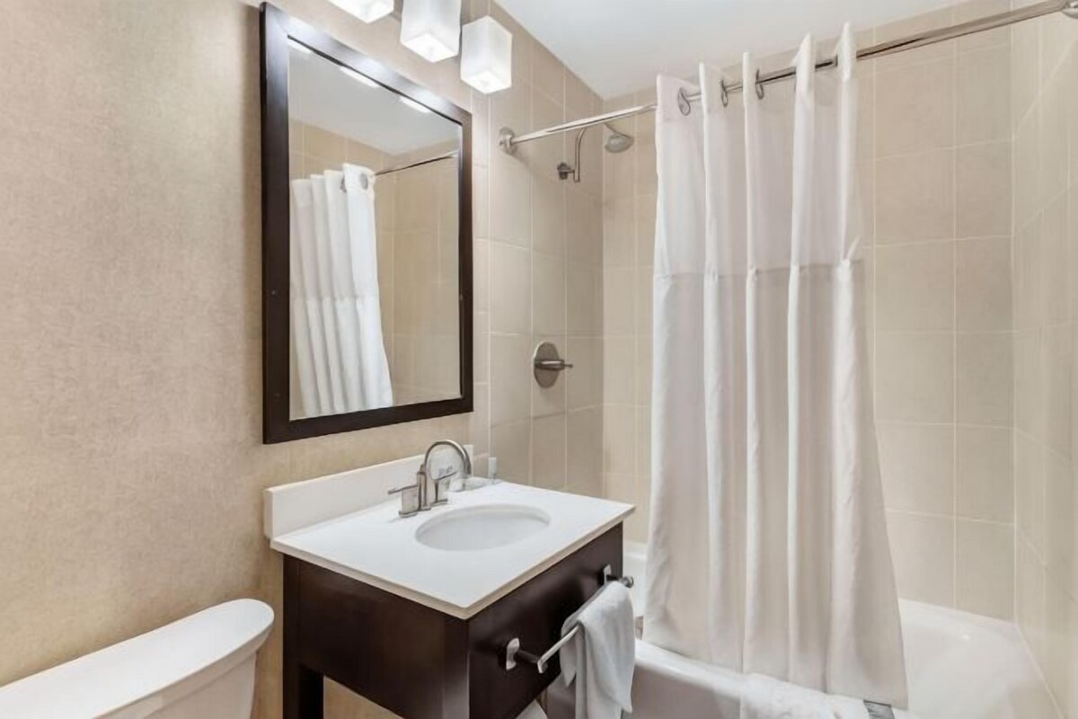 A bathroom with a sink, mirror, toilet, and shower curtain.