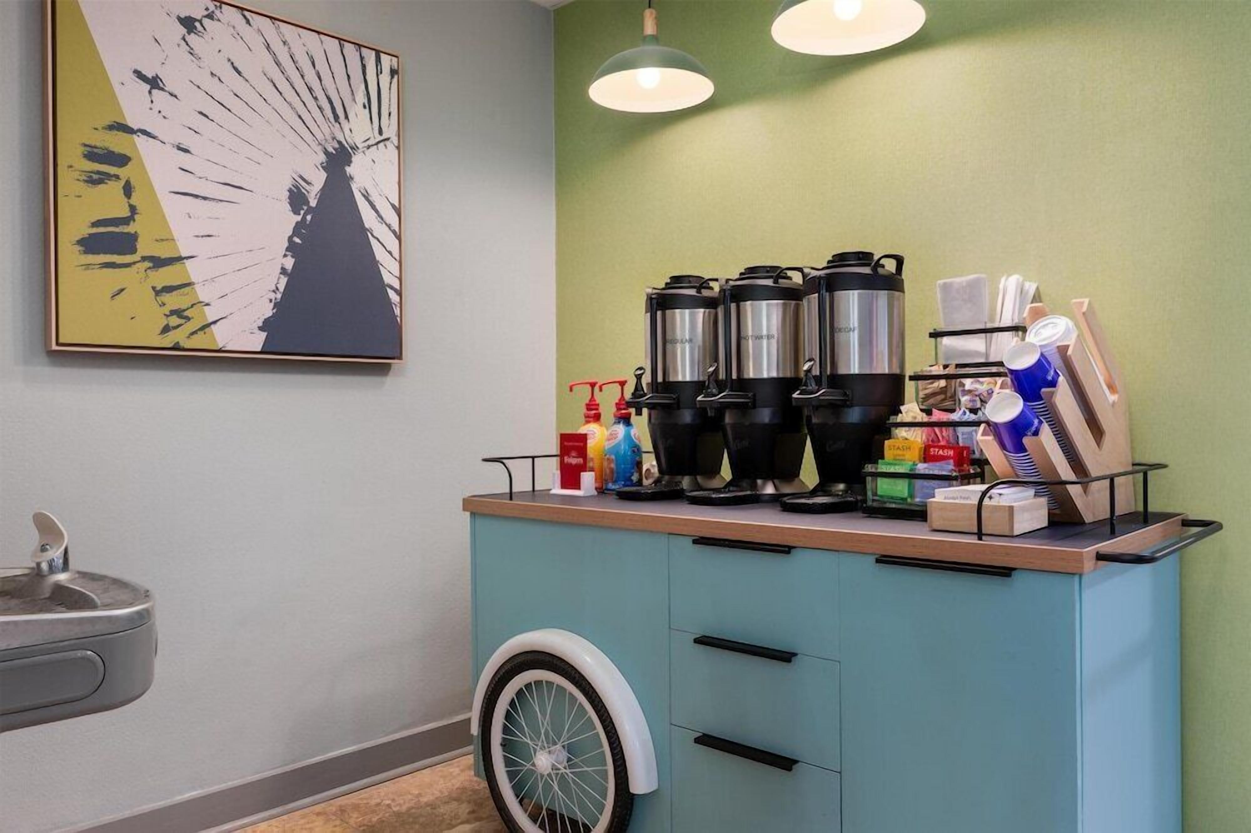 A kitchenette with a coffee maker, kettles, and a small fridge.