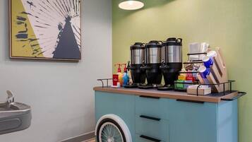 Una kitchenette equipada con cafetera, hervidoras y un refrigerador pequeño.