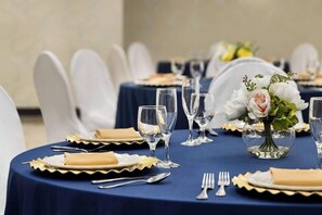 A table set with plates, cutlery, and glasses, with a vase of flowers in the center. - Wyndham Garden Totowa (Totowa)