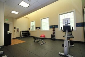 A gym with exercise equipment, a reception desk, and a wall-mounted fire extinguisher. - Hampton Inn Portland Airport (South Portland)
