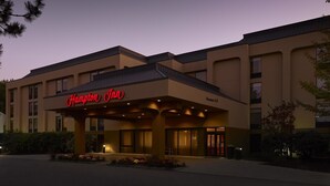 A Hampton Inn hotel with a modern facade, large windows, and a prominent entrance. - Hampton Inn Portland Airport (South Portland)
