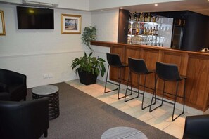 Eine Bar mit Hockern, einem an der Wand befestigten Fernseher und einem Blumentopf.