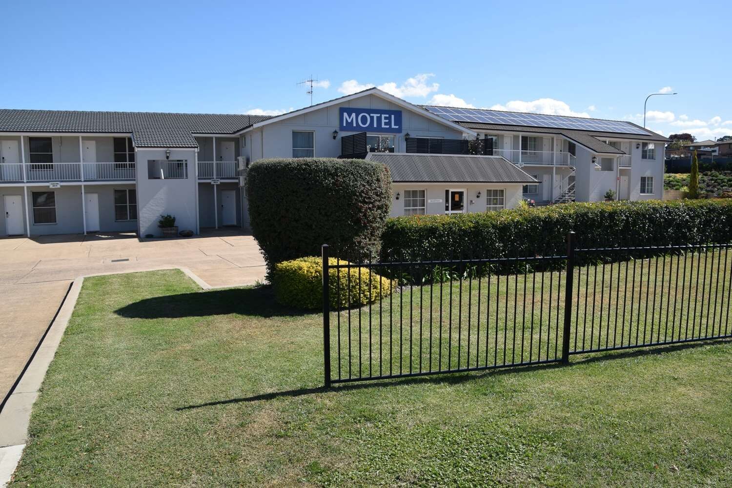 A motel with a sign, a parking lot, and a well-maintained lawn.