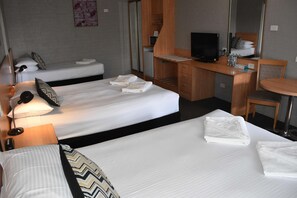Habitación de hotel con dos camas, un escritorio, un televisor, una silla y una mesita.