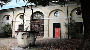 Un edificio con finestre ad arco, una grande fontana in pietra e una porta rossa.