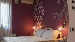 Ein Schlafzimmer mit einem Bett, zwei Nachttischlampen, einem Nachttisch und einer Wand mit floralem Muster.