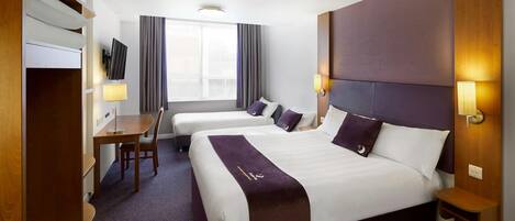 Une chambre d’hôtel avec deux lits, un bureau, une télévision et une fenêtre avec des rideaux.
