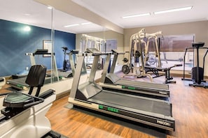 A gym with treadmills, a weight machine, and a rowing machine.