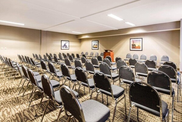 A conference room with rows of chairs, a podium, and framed pictures on the walls.