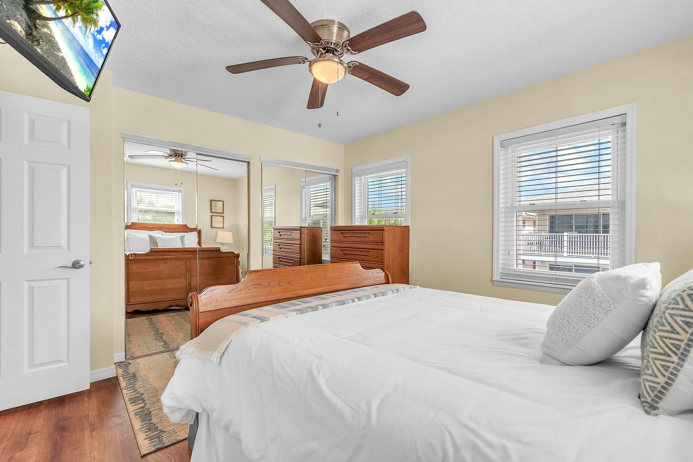 Une chambre à coucher avec un lit, un ventilateur de plafond et de grandes fenêtres.
