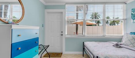 Un dormitorio con cama, cómoda, ventilador de techo y ventana con persianas.