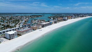 Eine Küstenstadt mit breitem Sandstrand, einer Marina und mehreren mehrstöckigen Gebäuden.