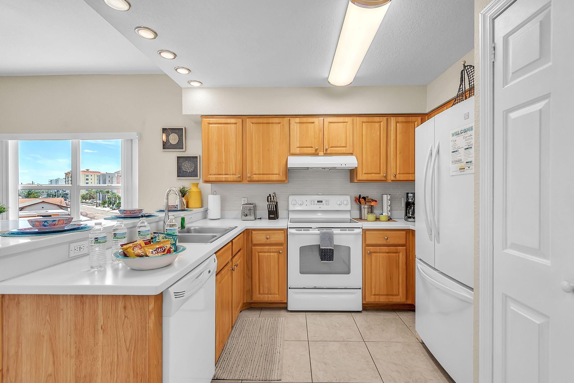 A modern kitchen with wooden cabinets, white appliances, and a view of the city.