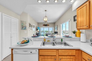 A kitchen with a large island, double sink, wooden cabinets, and a view to the outside. - Skyline of Madeira 306 (Madeira Beach)
