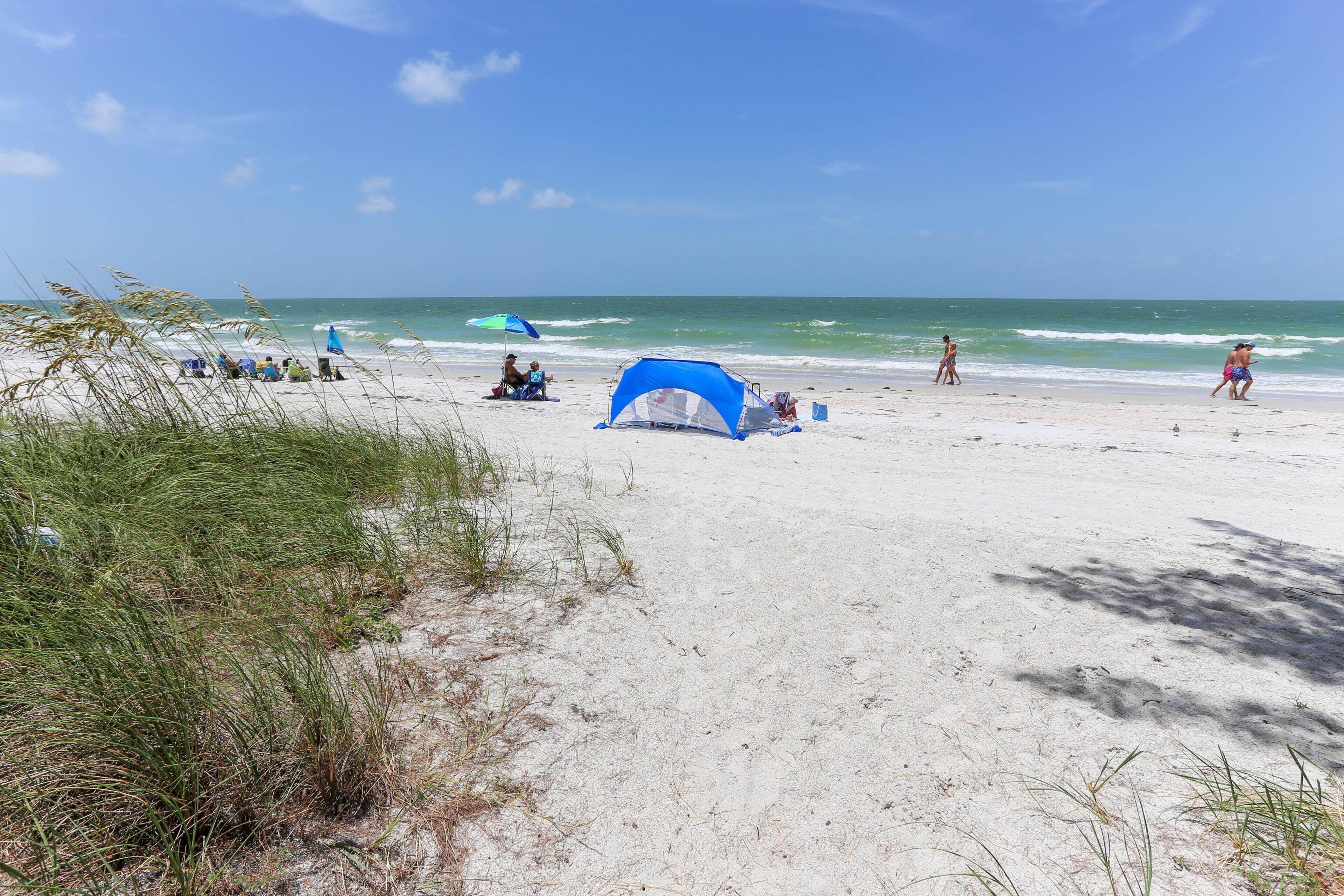 A beach with a tent, people, and a clear sky.