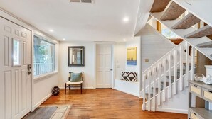 A hallway with wooden flooring, a bench, a door, a mirror, and a staircase with stone steps. - Sunset Beach House (Treasure Island)