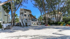 A beachfront property with multiple-story houses, a sandy beach, and a white picket fence. - Sunset Beach House (Treasure Island)