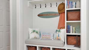 Una habitación blanca con una banca, estanterías y objetos decorativos.