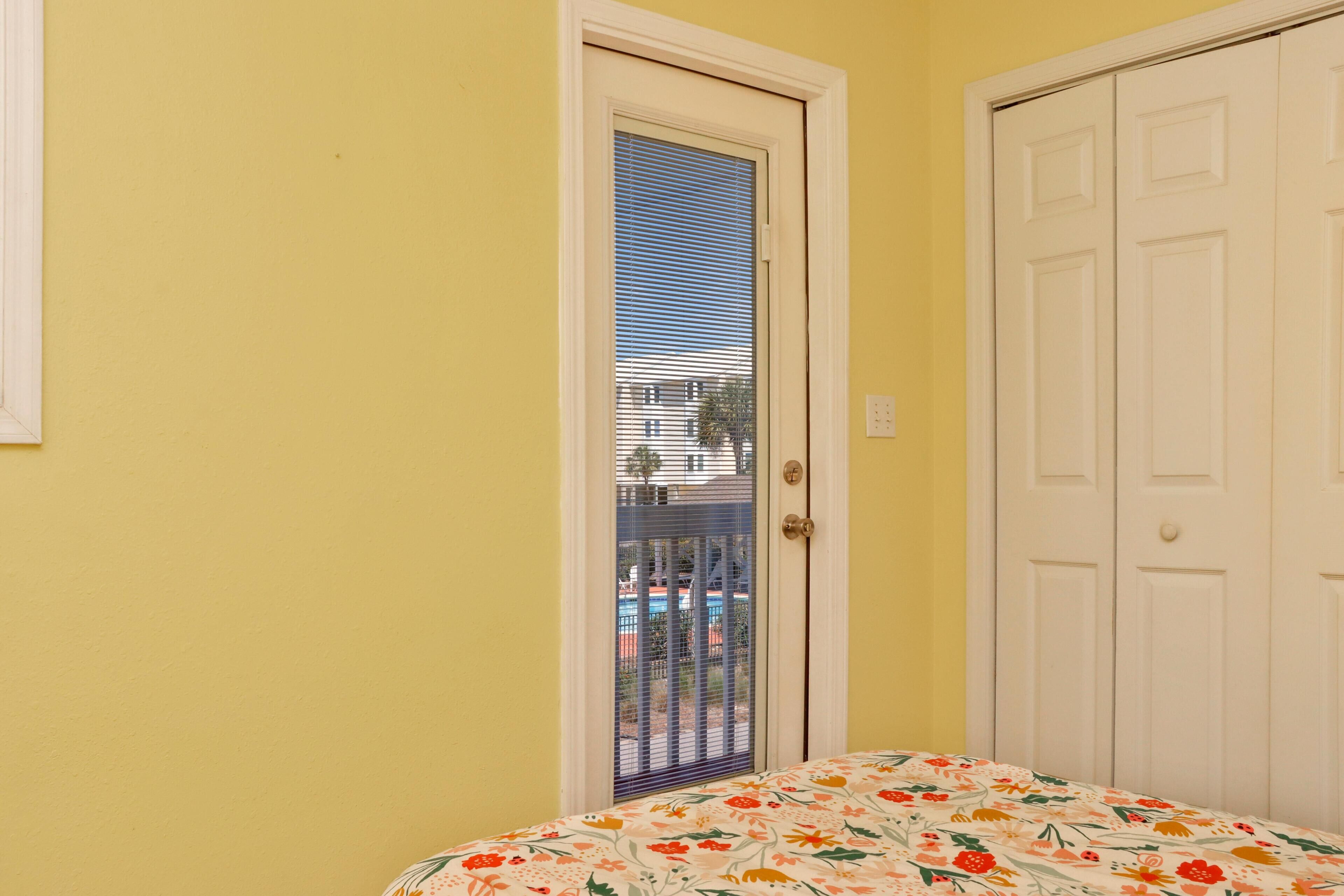 Una habitación con cama, puerta y vista por una ventana.