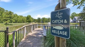 A wooden dock leading to a lake with a sign indicating a catch and release fishing area. - Juniper Presents: Chalet #80 Family Fun w Pools & Resort Perks (Stevensville)