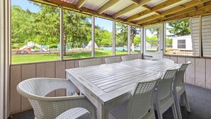 A covered outdoor area with a table and chairs, large windows, and a view of a playground. - Juniper Presents: Chalet #80 Family Fun w Pools & Resort Perks (Stevensville)