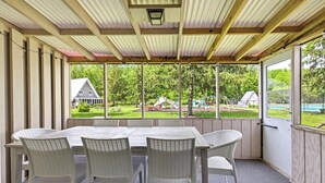 A covered patio with a table and chairs, large windows, and a view of a playground. - Juniper Presents: Chalet #80 Family Fun w Pools & Resort Perks (Stevensville)