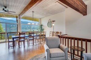 A dining area with wooden furniture, a grey armchair, and a view of a lake.