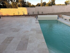 A swimming pool with a tiled deck, surrounded by a low wall and a small garden area. - Home Exchange in Orgnac l'Aven (Orgnac-l'Aven)