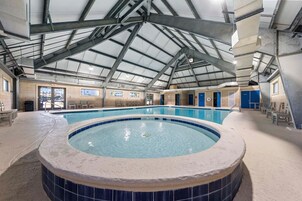 Una piscina interior con hidromasaje, techo cubierto y vistas al exterior.