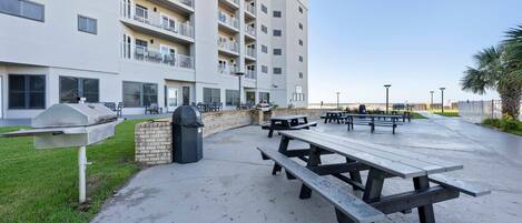 Un edificio residencial de varios pisos con balcones, mobiliario exterior y una zona de barbacoa.