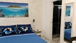 A bedroom with a bed, a nightstand, a bathroom mirror, and a door leading to a shower area. - The Colors of the Sea - Turquoise Studio Apartment (San Pietro In Bevagna)