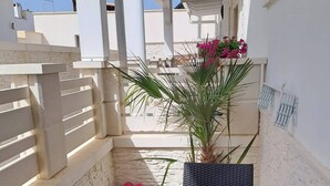 A covered outdoor area with a table and chairs, a potted plant, and a stone wall. - The Colors of the Sea - Turquoise Studio Apartment (San Pietro In Bevagna)