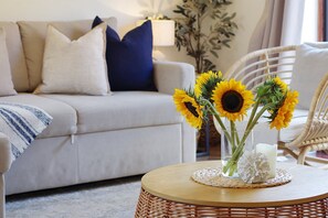 A living room with a sofa, a round coffee table with a vase of sunflowers, and a lamp. - The Nook by Lil Blu Stays (Bournemouth, Christchurch and Poole)