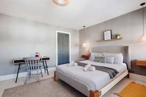Un dormitorio con cama, escritorio, silla y puerta.