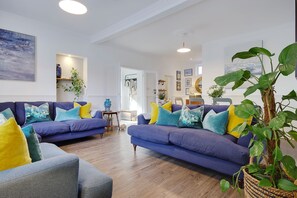 Ein Wohnzimmer mit zwei Sofas, einem Couchtisch und einer großen Pflanze.