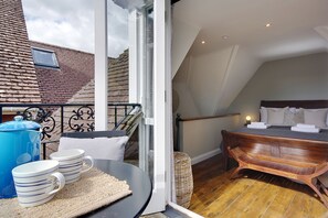 Ein Schlafzimmer mit einem hölzernen Bett, einem kleinen Fenster und einem Balkon mit einem blauen Wasserkocher und Tassen.