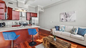 A modern kitchen with a central island, bar stools, a dining table, and a living area with a sofa and decorative pillows. - Chic Modern 1BD | Northern Libs | Sleeps 2 Stay (Philadelphia)